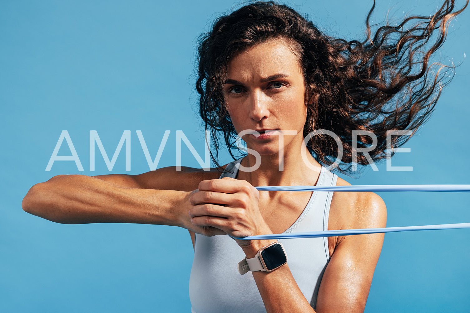 Close up of fit and muscular woman using resistance band against blue background