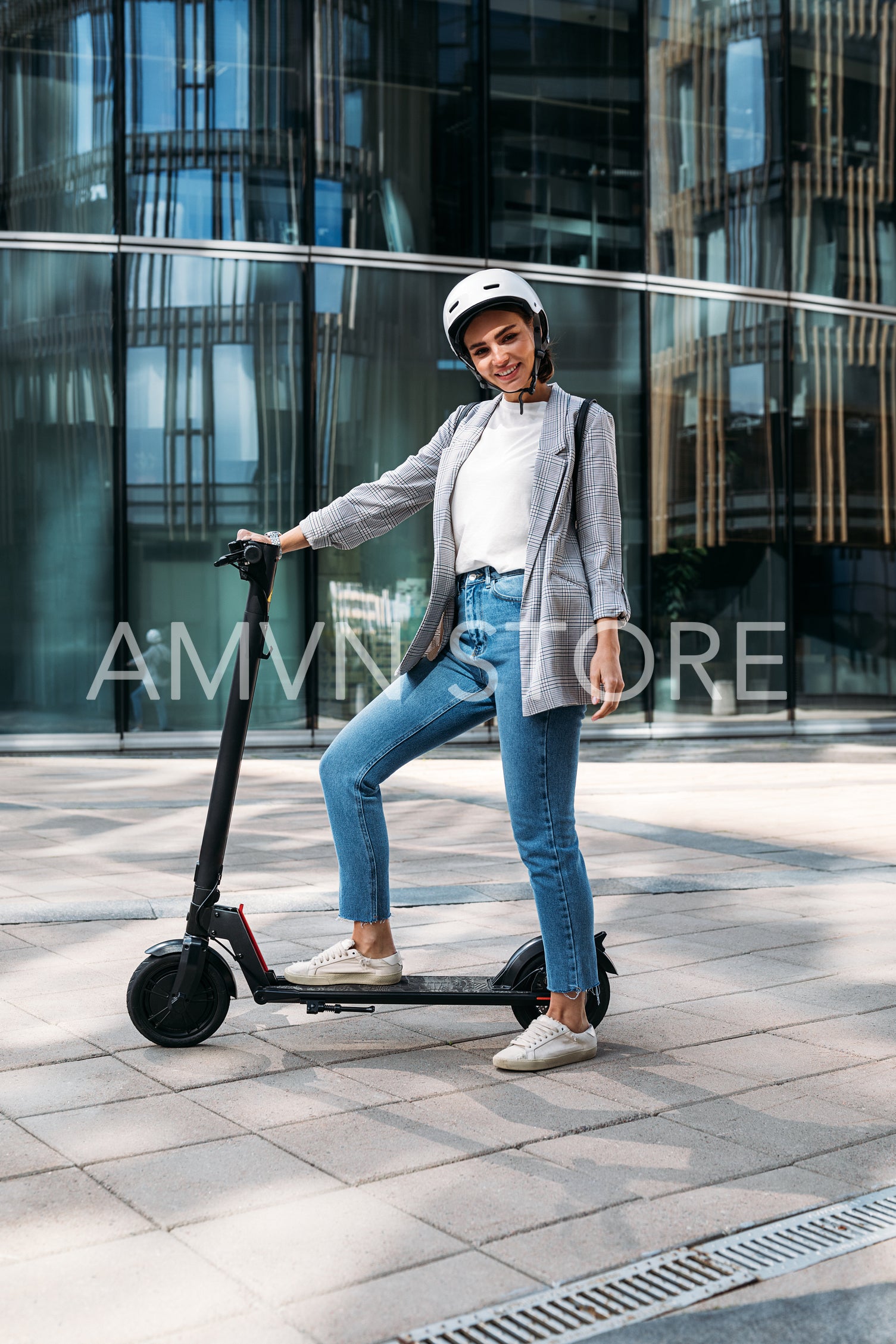 Young cheerful woman standing in the city with electric push scooter