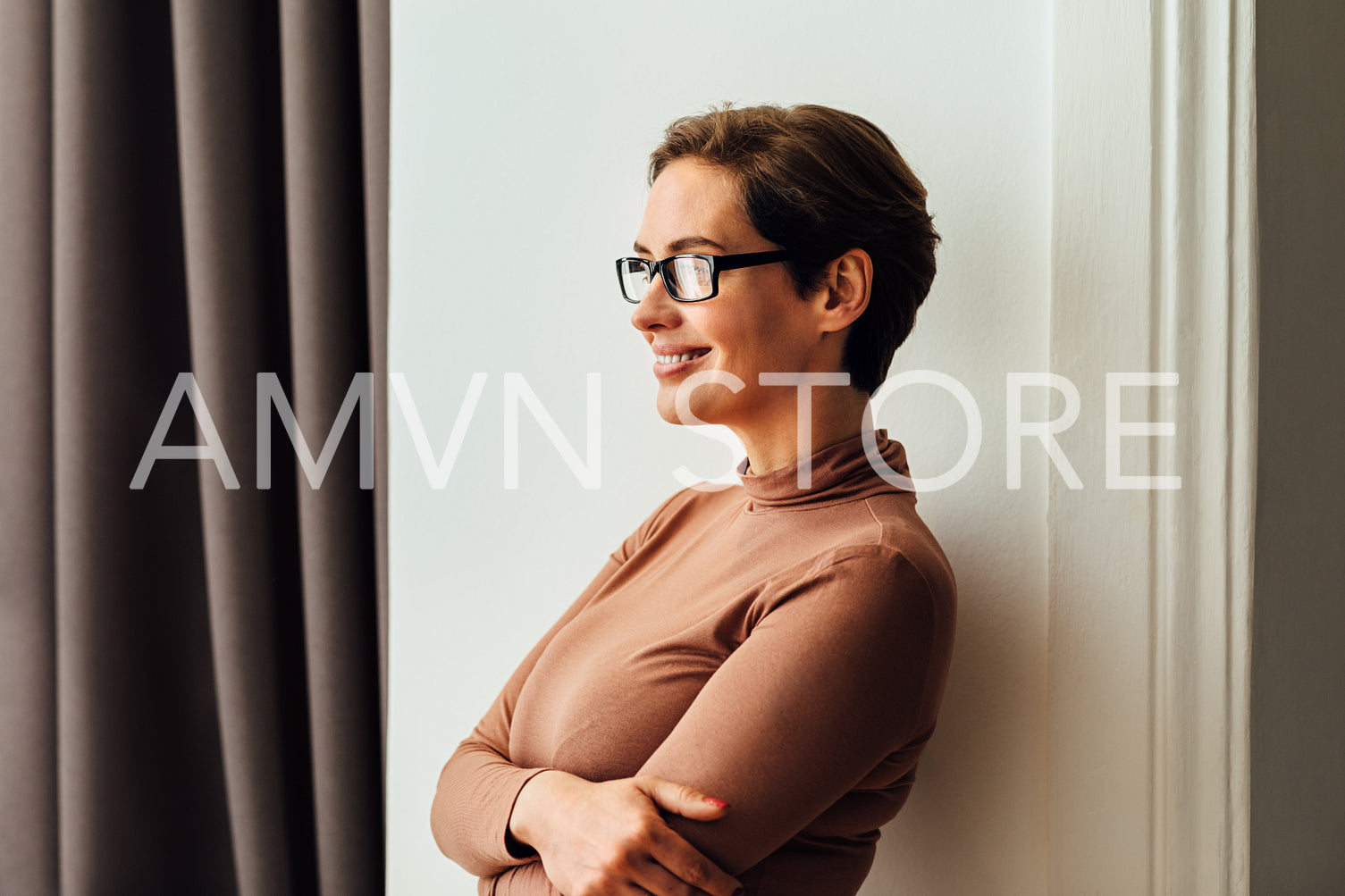 Side view of a beautiful businesswoman in eyeglasses standing in hotel room and looking at window	