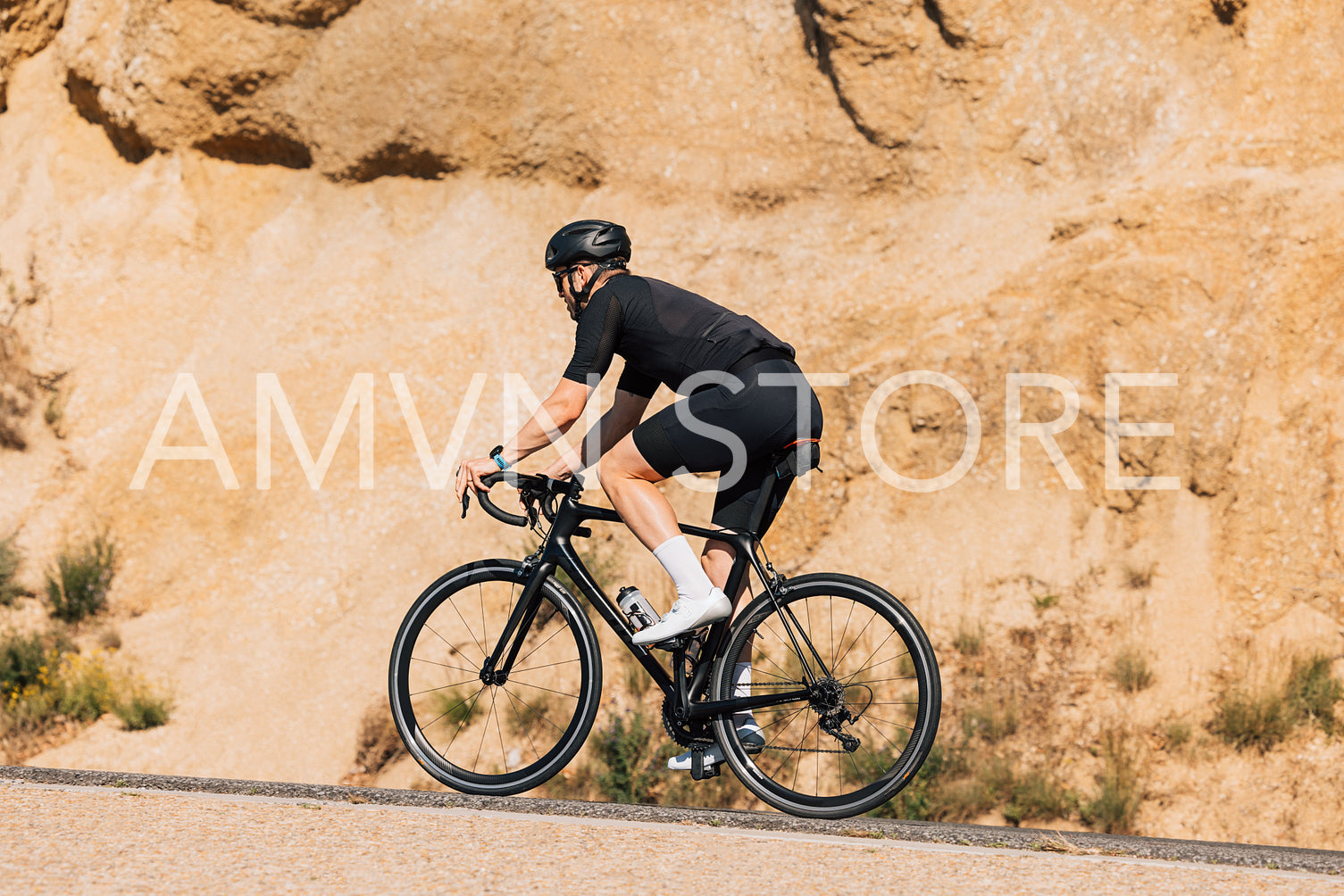 Male cyclist in black sportswear practicing on a countryside road