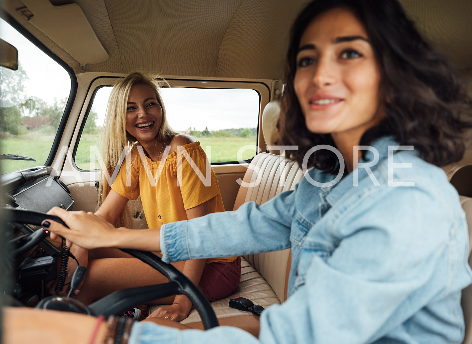 Smiling blond woman on a passenger seat looking at her friend while traveling by a van