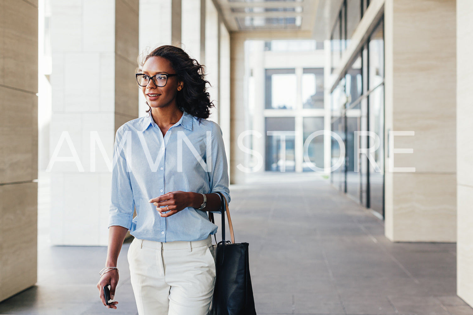 Female business professional walking outside an office building with bag on a hand