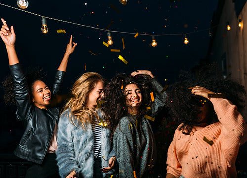 Group of female friends under confetti. Women having fun outdoors.