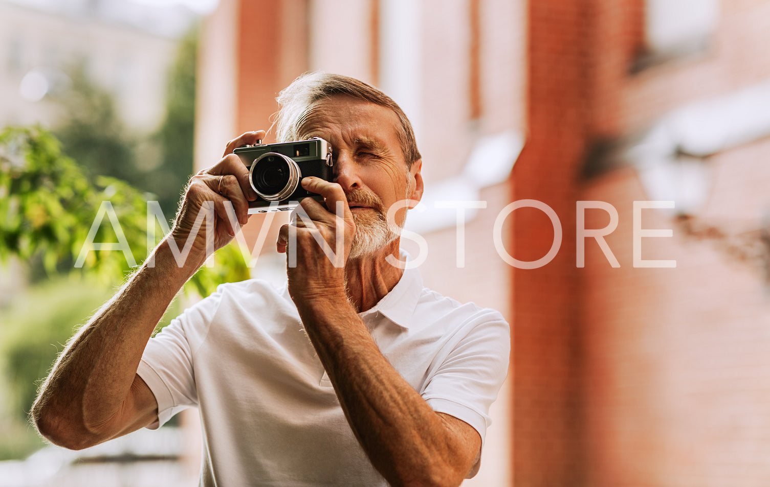 Portrait of a senior photographer taking photographs with an analog camera outdoors	