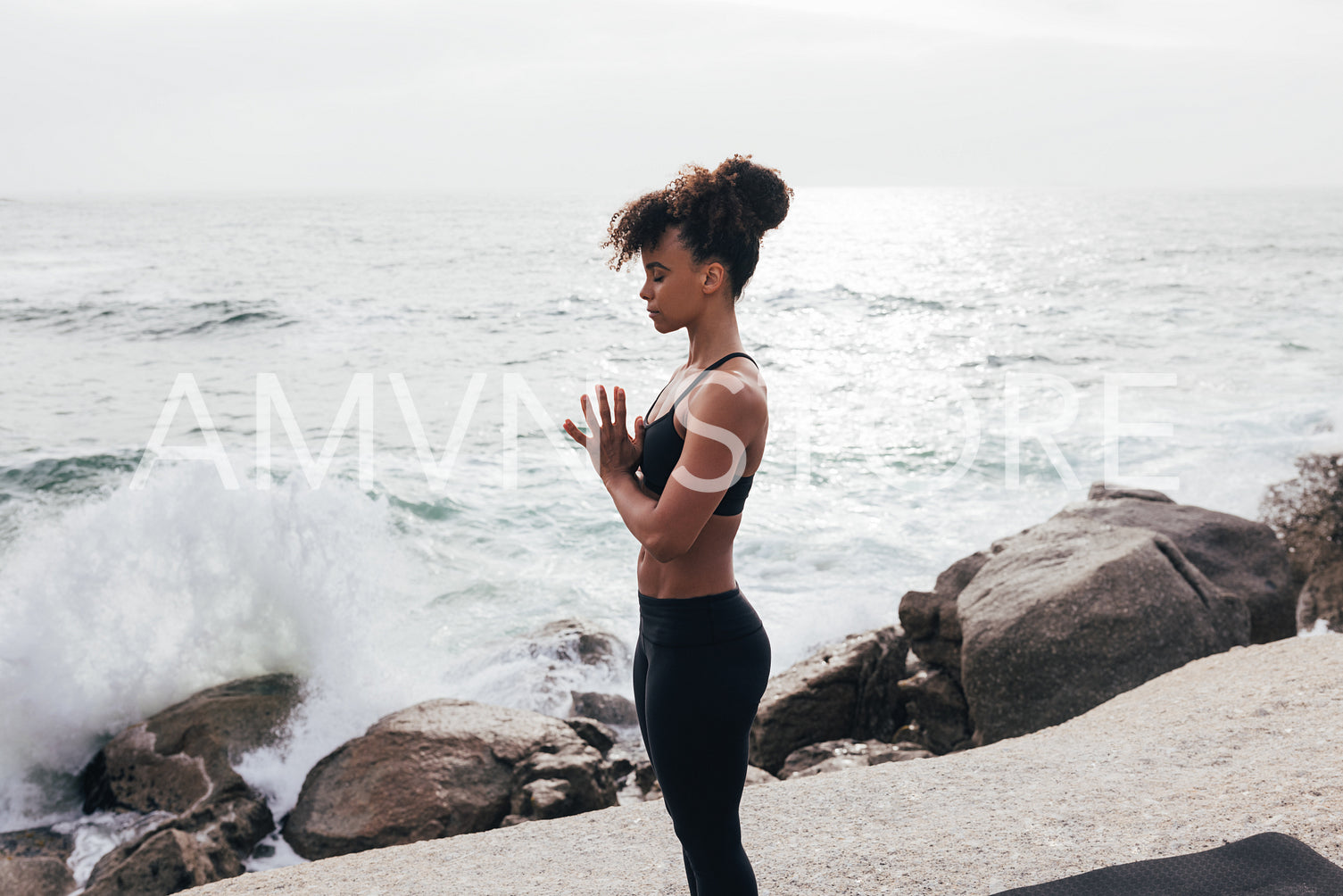 Side view of slim woman in sportswear folded hands with closed eyes