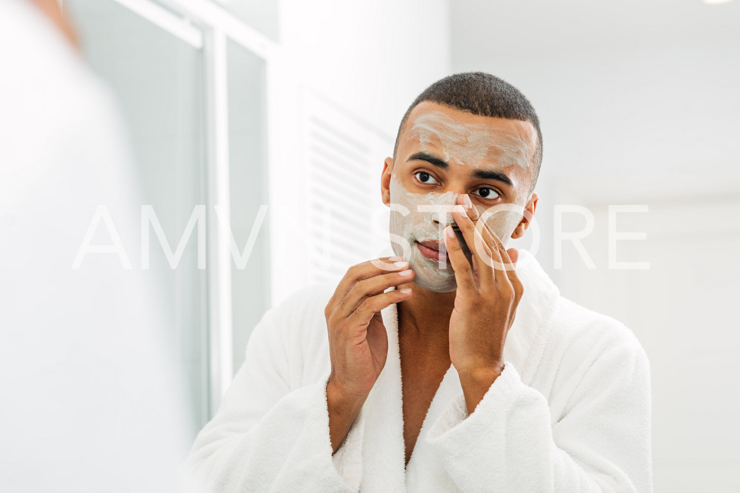 Man looking in the mirror with white clay mask on his face	