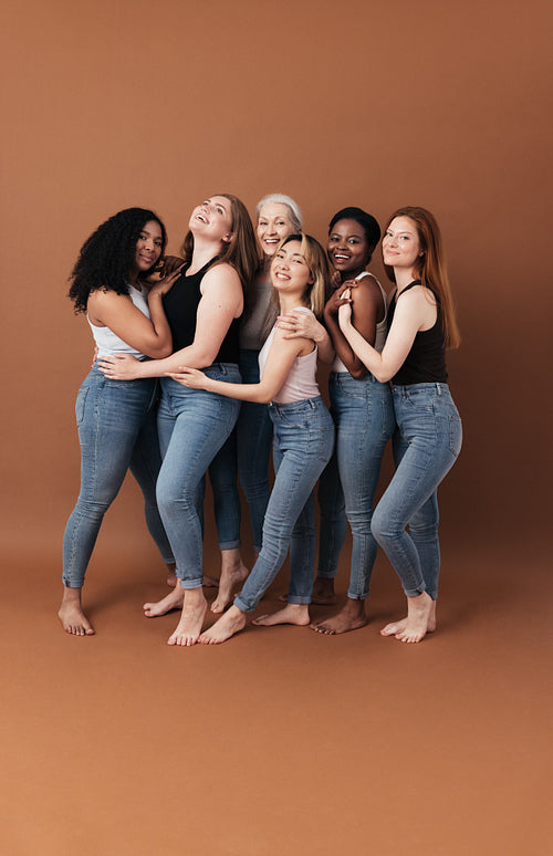 Group of cheerful women of different body type and ages standing together in a studio