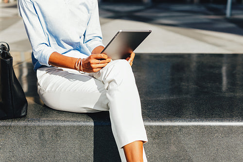 Unrecognizable businesswoman using a digital tablet while sitting outdoors