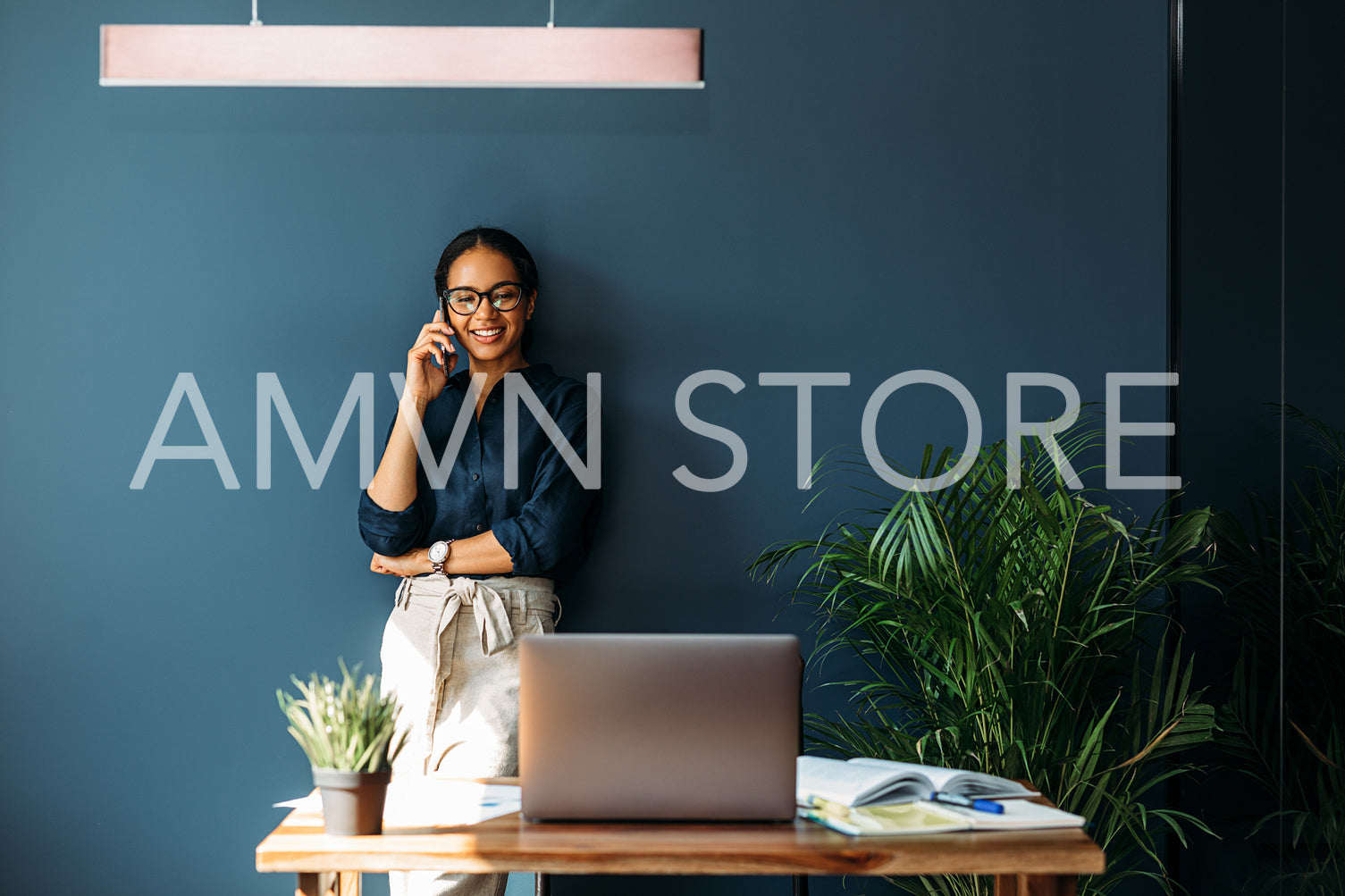 Businesswoman leaning on a wall in the living room talking on mobile phone	