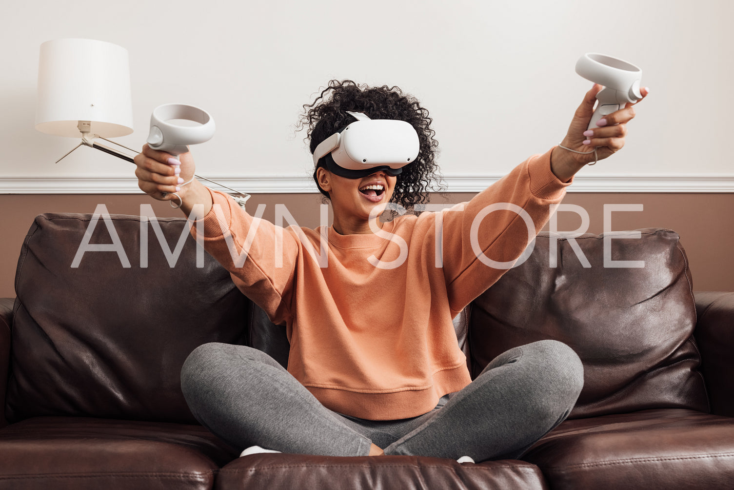 Cheerful mixed race woman sitting on a couch with VR headset