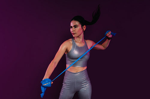 Slim woman wearing silver fitness attire exercising with resistance band