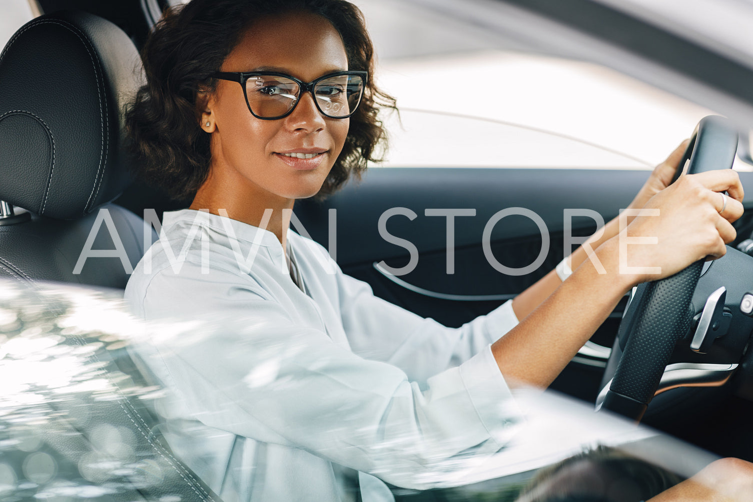 Young woman driving a car. Smiling female looking at camera while sitting on driver seat.	