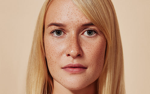 Close-up studio portrait of a blond female with freckles. Cropped shot of woman with smooth skin. Highly detailed image of a young female with perfect skin.