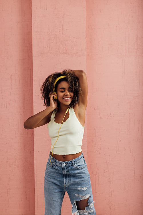 Cheerful woman in casual clothes enjoying music listening by yel