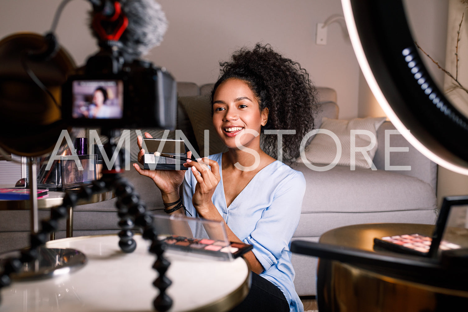 Smiling woman holding a makeup palette while recording her video for blog	