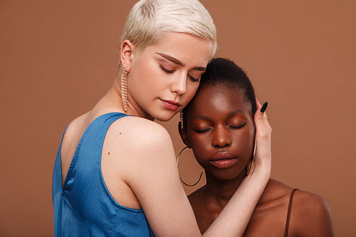 Two women with a different skin colors standing head to head with closed eyes