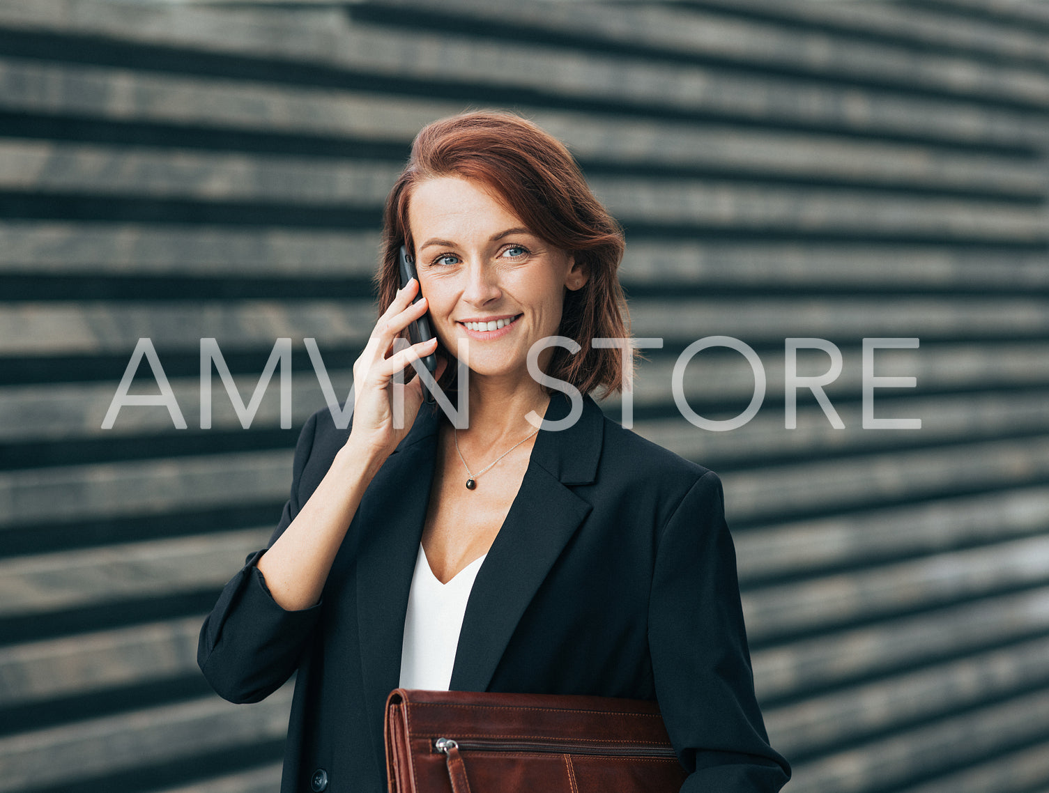 Smiling middle-aged businesswoman making a phone call and looking at the camera