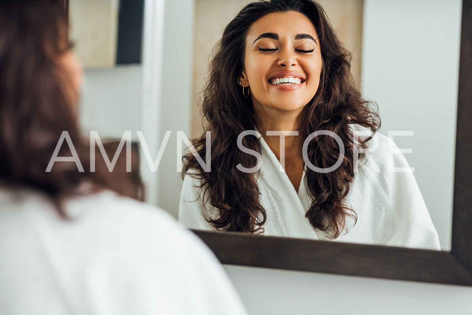 Happy woman with closed eyes standing in front of a mirror in bathroom	