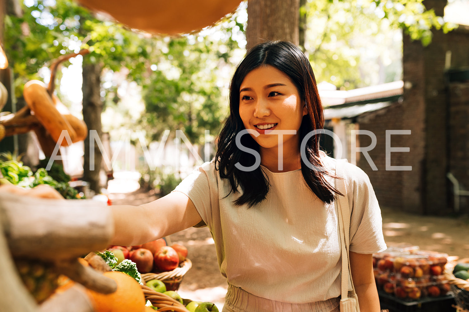 Young smiling woman in casuals buying fruits at a local market