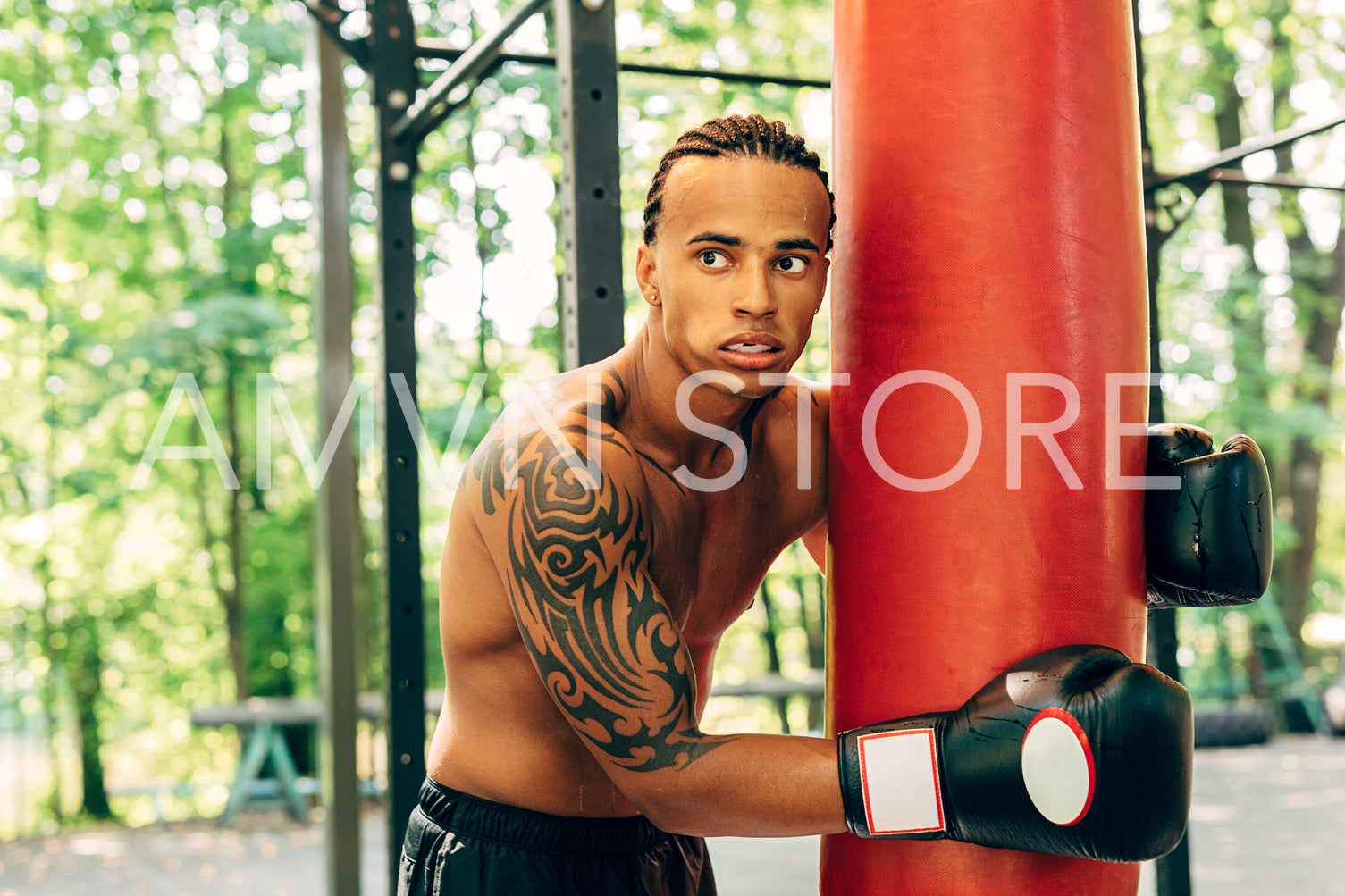 Man boxer leaning to rest on a punching bag at the sports ground	