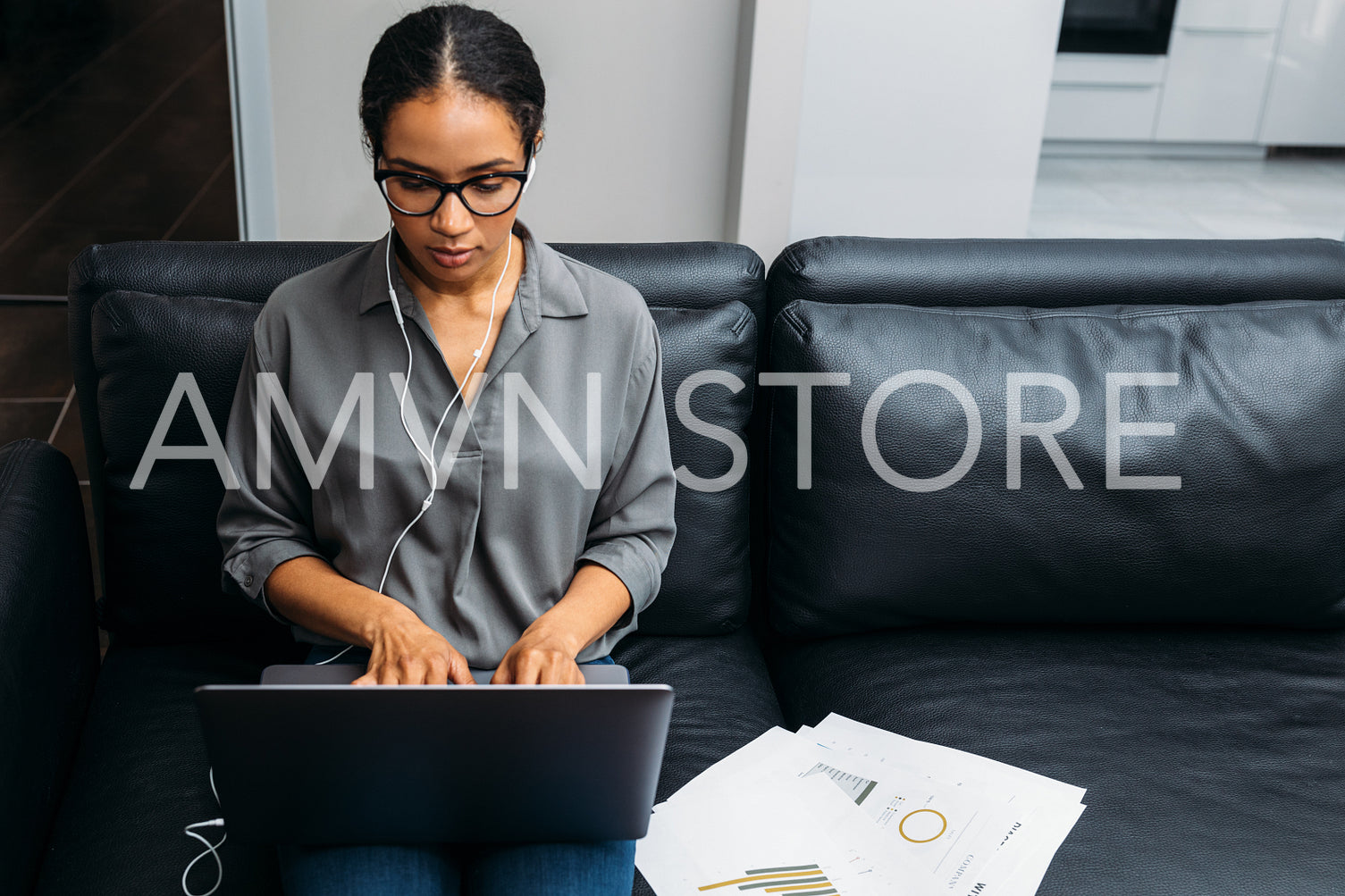 Front view of a young woman working online with documents while sitting on sofa	