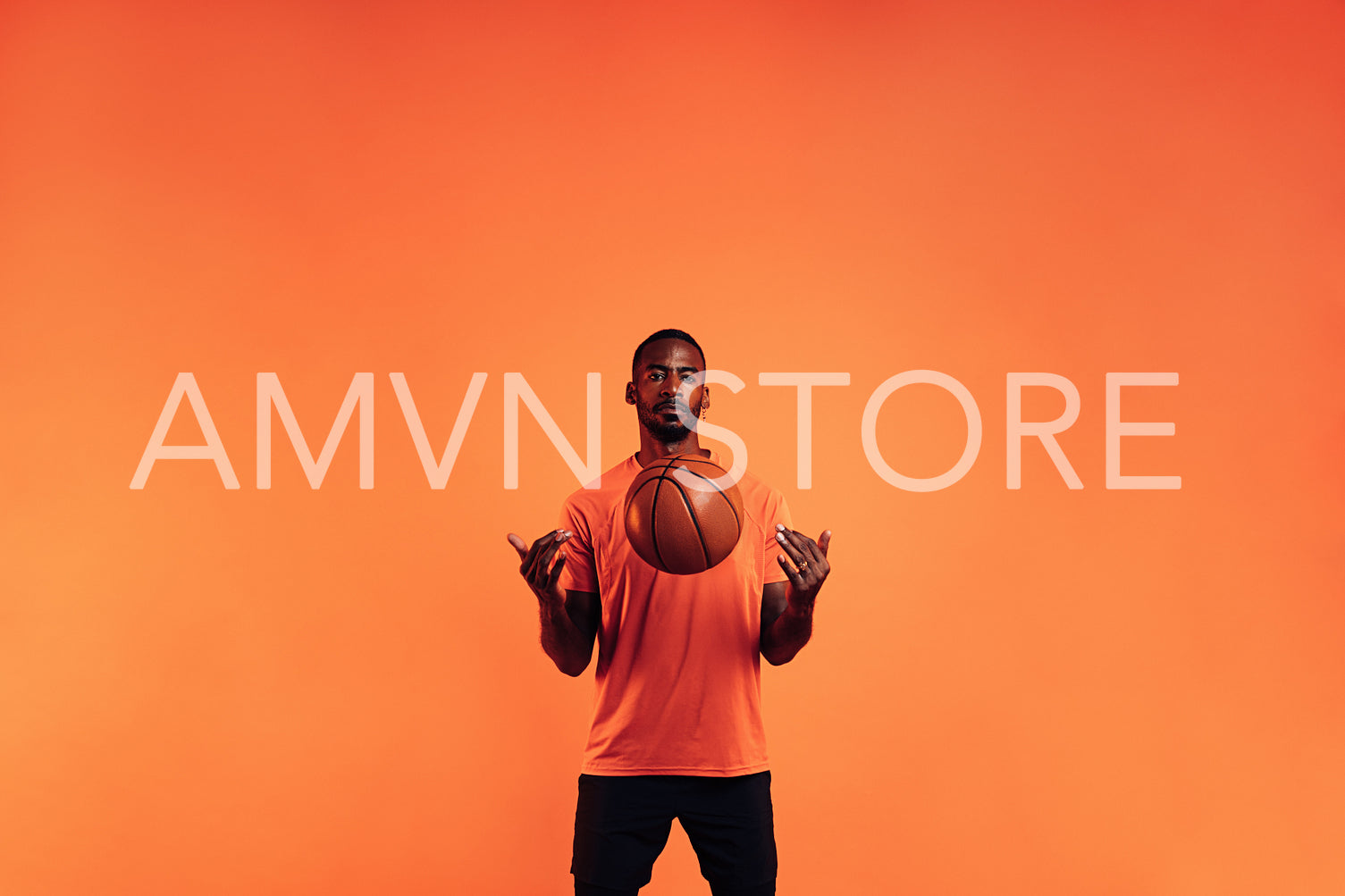 Serious guy in sportswear throws a basketball in front of him in the studio