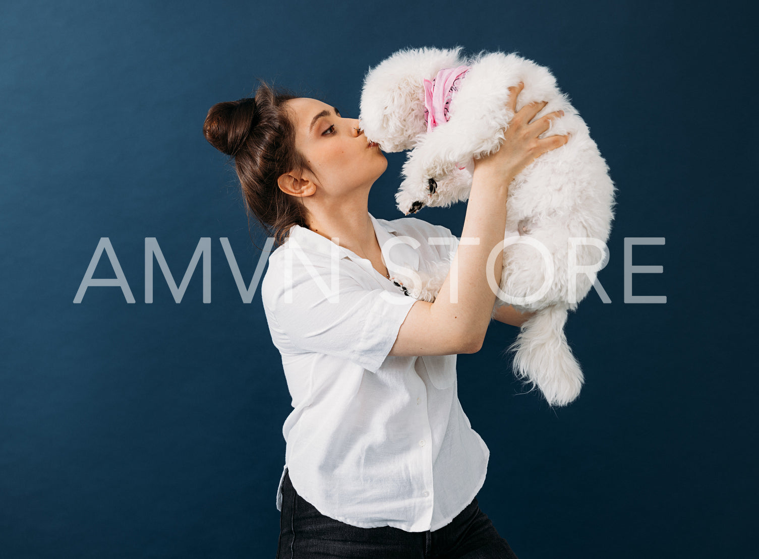 Side view of a woman holding and kissing her little white dog in