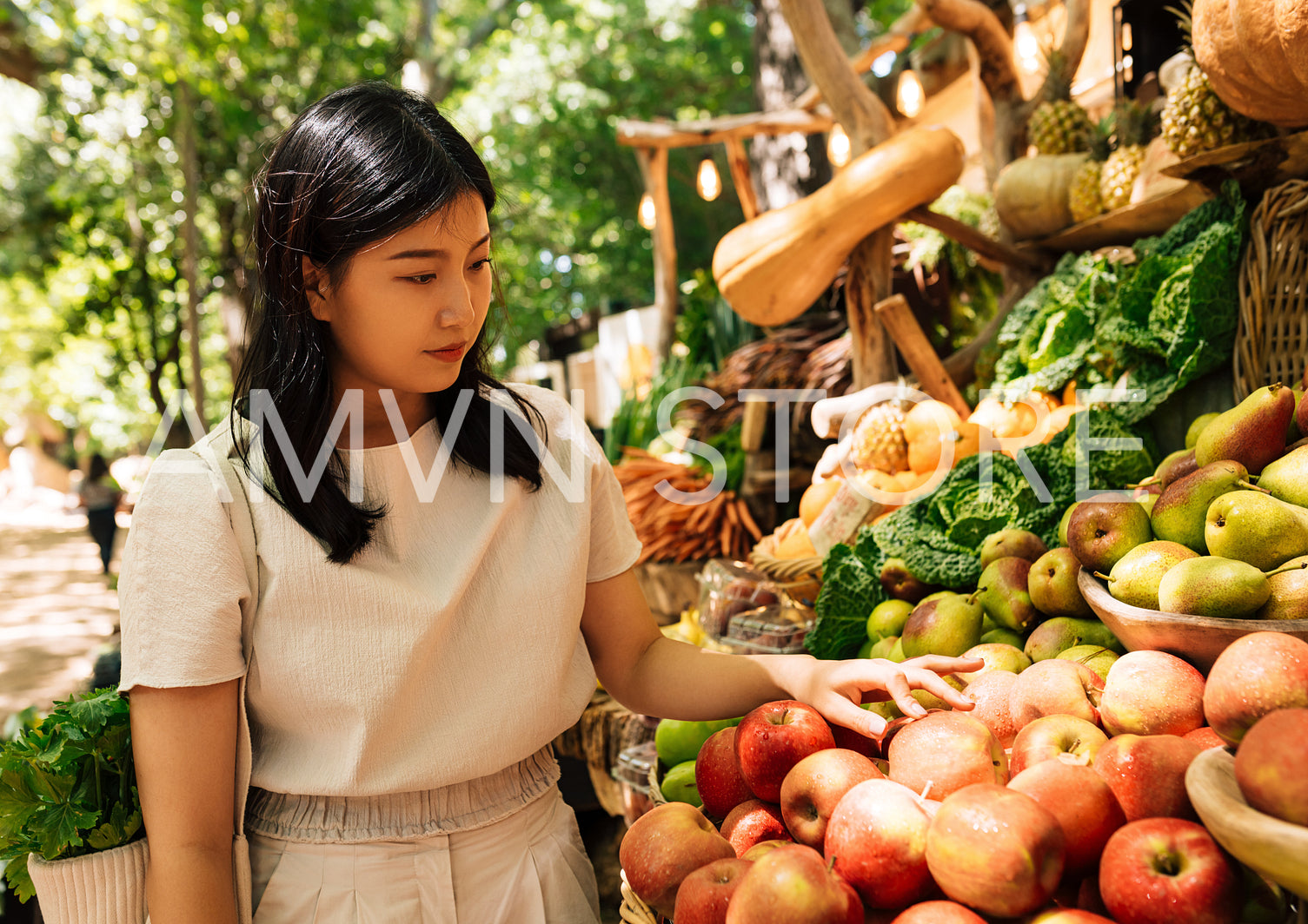 Woman choosing apples at a farmers market. Young female customer on street market looking for healthy food.