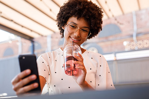 Woman drinking juice and photography on smartphone