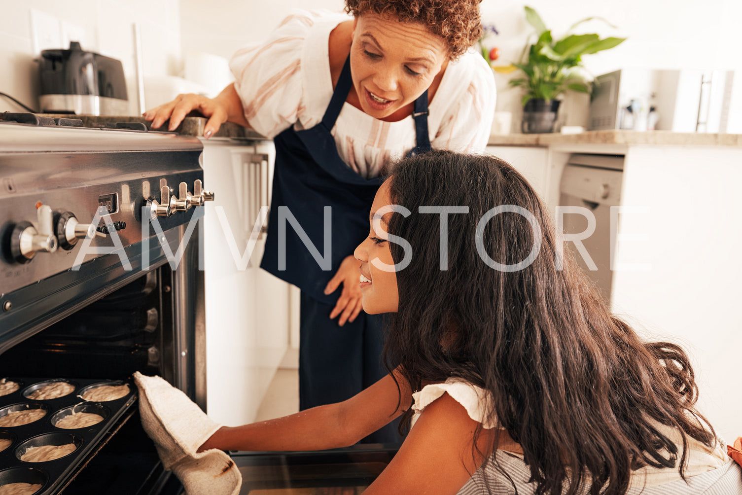 Girl and granny cook together. Grandmother teaching granddaughter how to bake cupcakes in the oven.