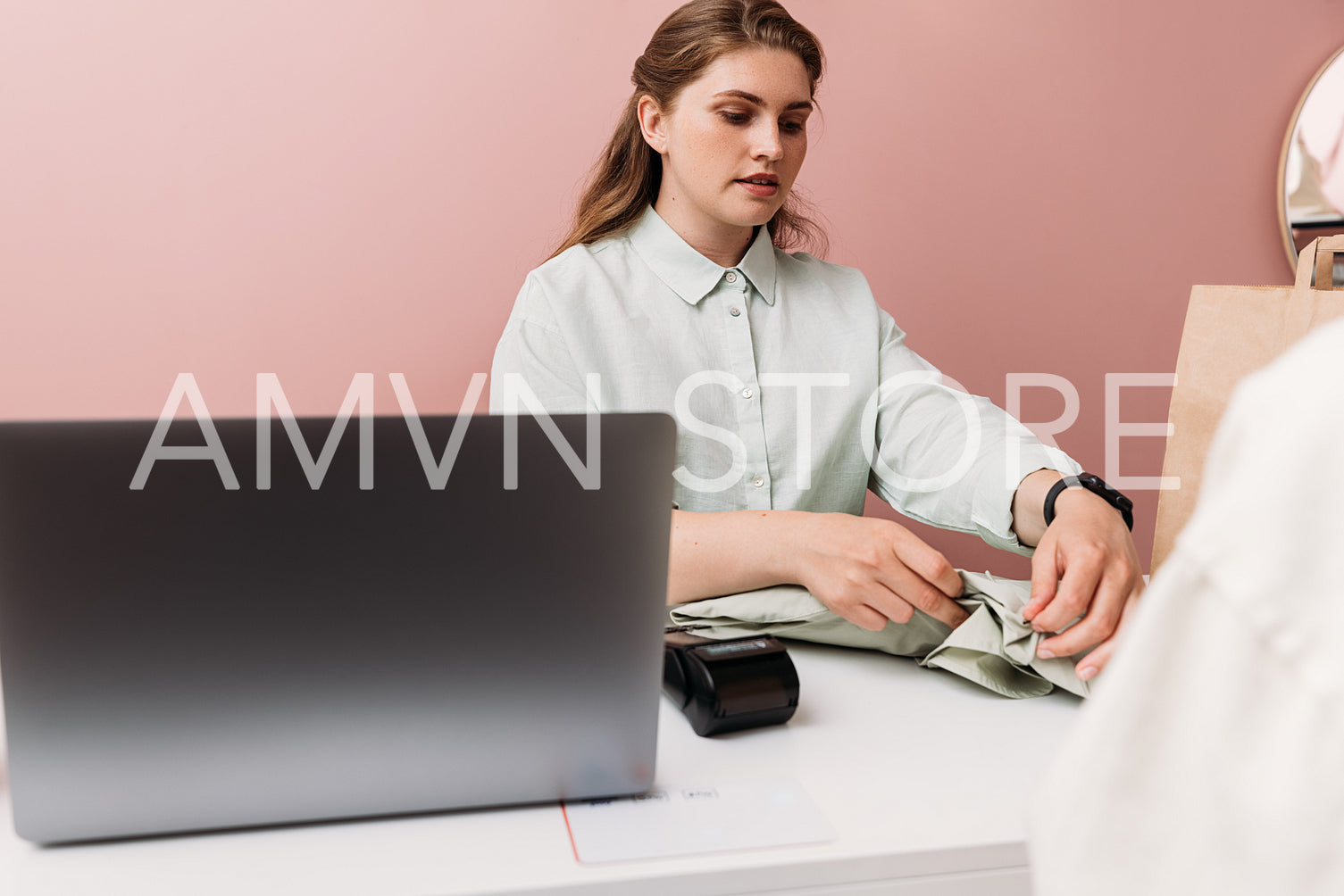 Small boutique owner folding clothes for customer at checkout co