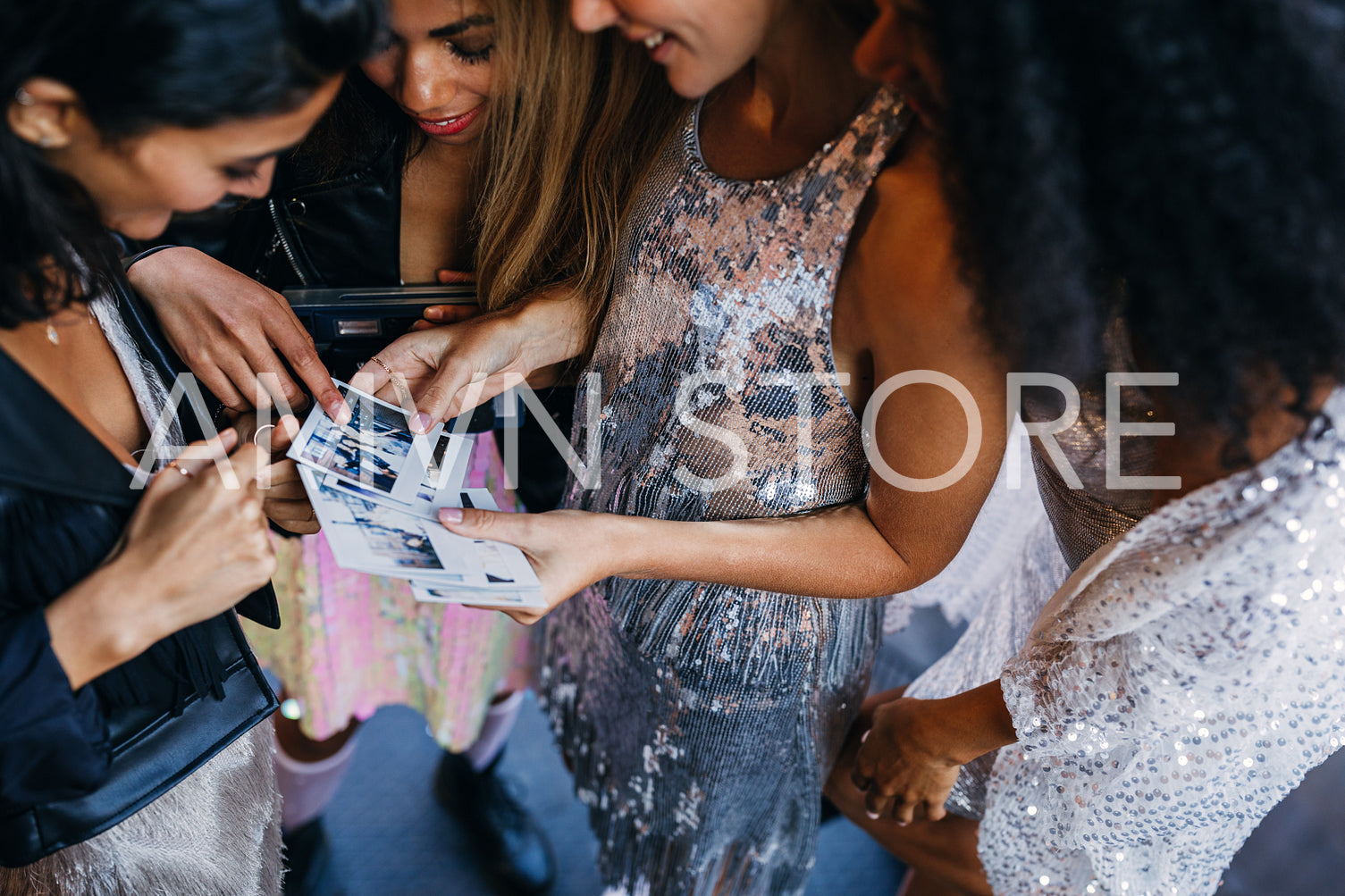 Unrecognizable women choosing instant photographs after party	