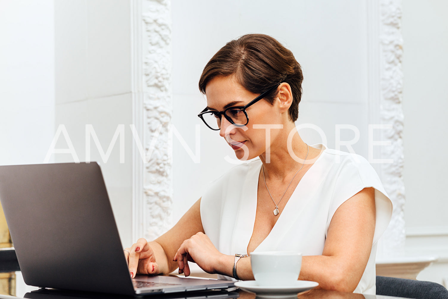 Caucasian woman typing on laptop while sitting at table in her apartment. Young female entrepreneur working from home.	