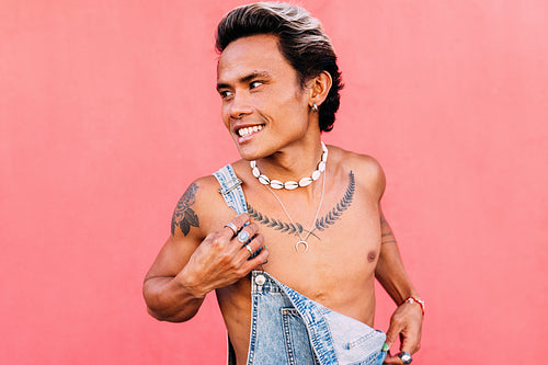 Young smiling man in denim overalls looking away outdoors