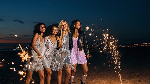 Four friends dressed up for party having fun outdoors at night