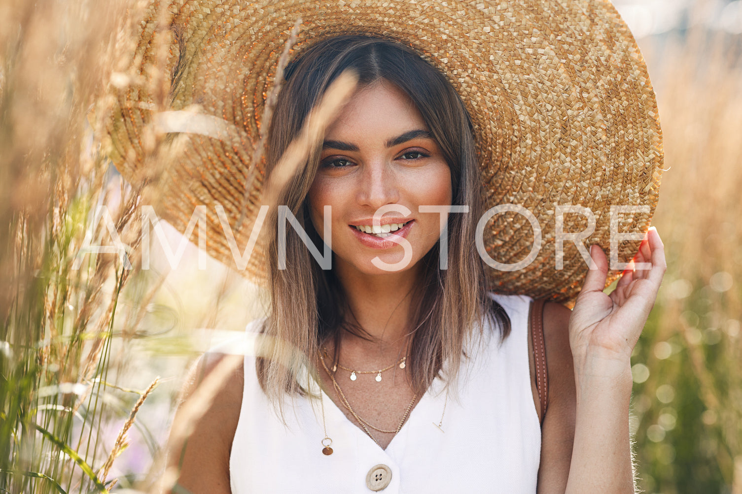 Cheerful female wearing a vintage straw hat. Smiling woman holds hat and looking at camera.	