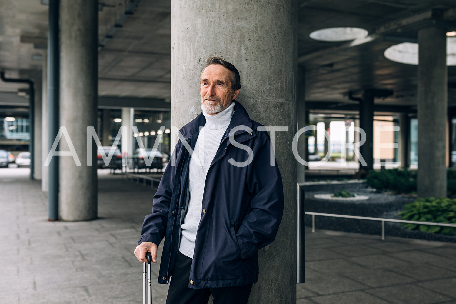 Stylish senior man standing outdoors at airport terminal looking away	