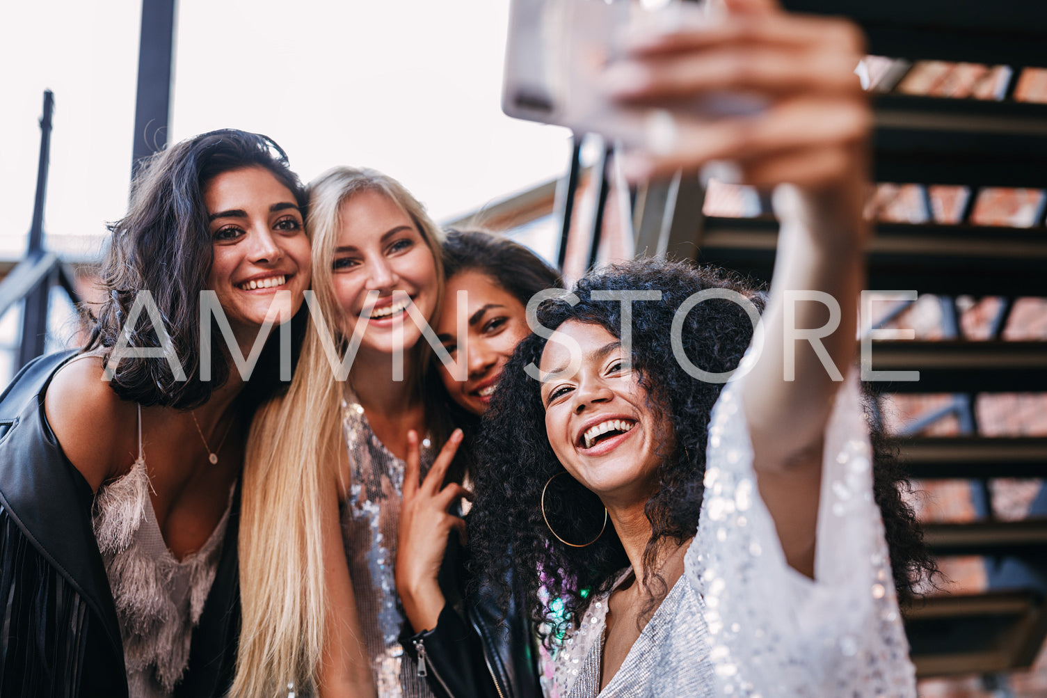 Happy friends looking at smartphone. Smiling women taking a selfie.	