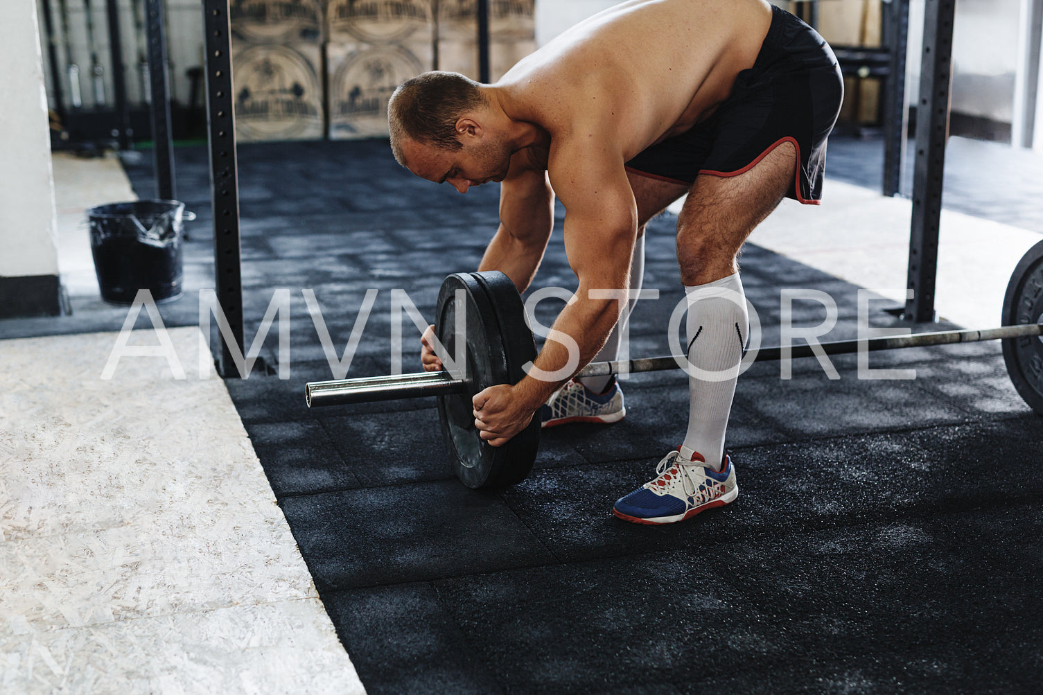 Young muscular athlete preparing barbell for deadlifting