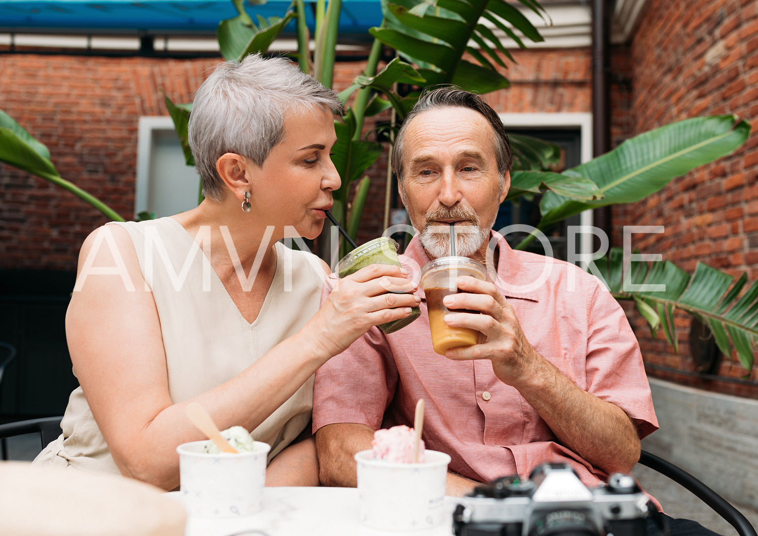 Mature couple sitting in an outdoor cafe and drinking cocktails