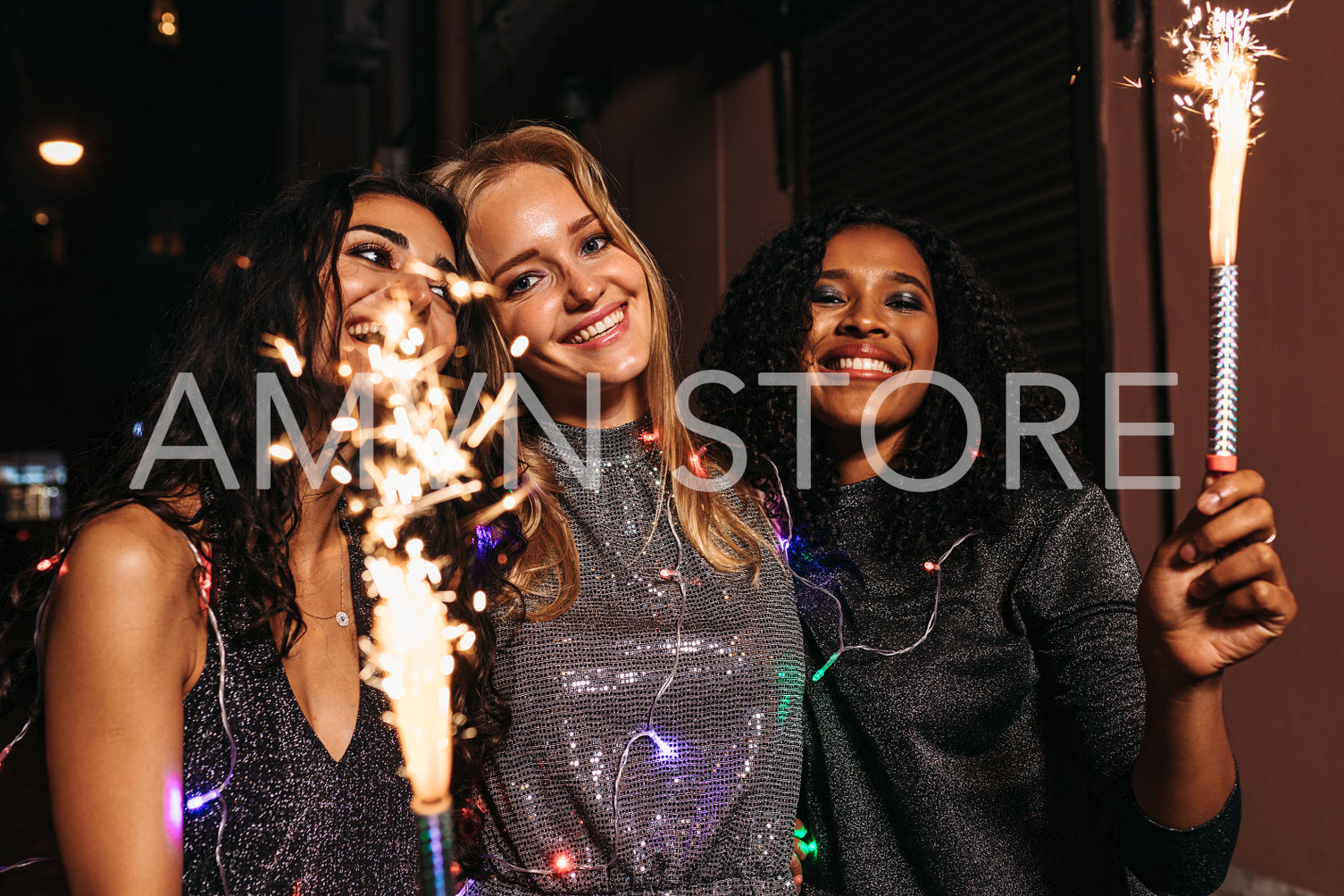 Young girls walking outdoors with sparklers and christmas lights around their bodies	