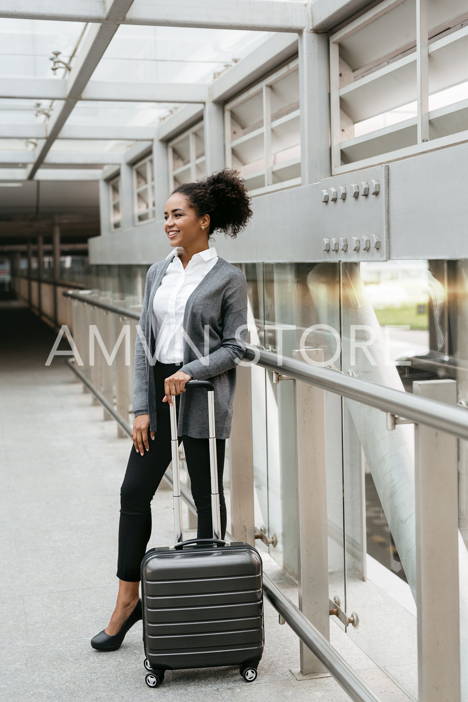 Smiling woman standing with suitcase in corridor at station	