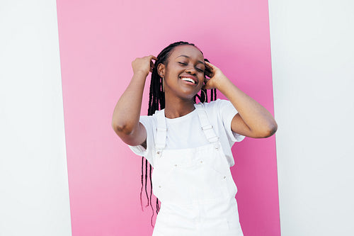 Young cheerful girl in white casuals standing against pink stripe outdoors