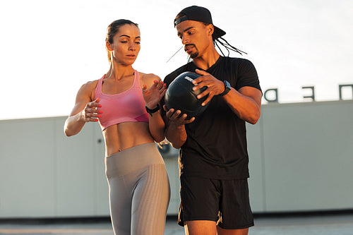 Man and woman exercising with a medicine ball on roof