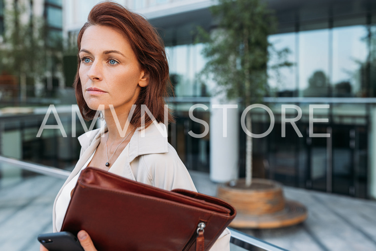 Close up portrait of a middle-aged businesswoman with ginger hair standing outdoors at an office building