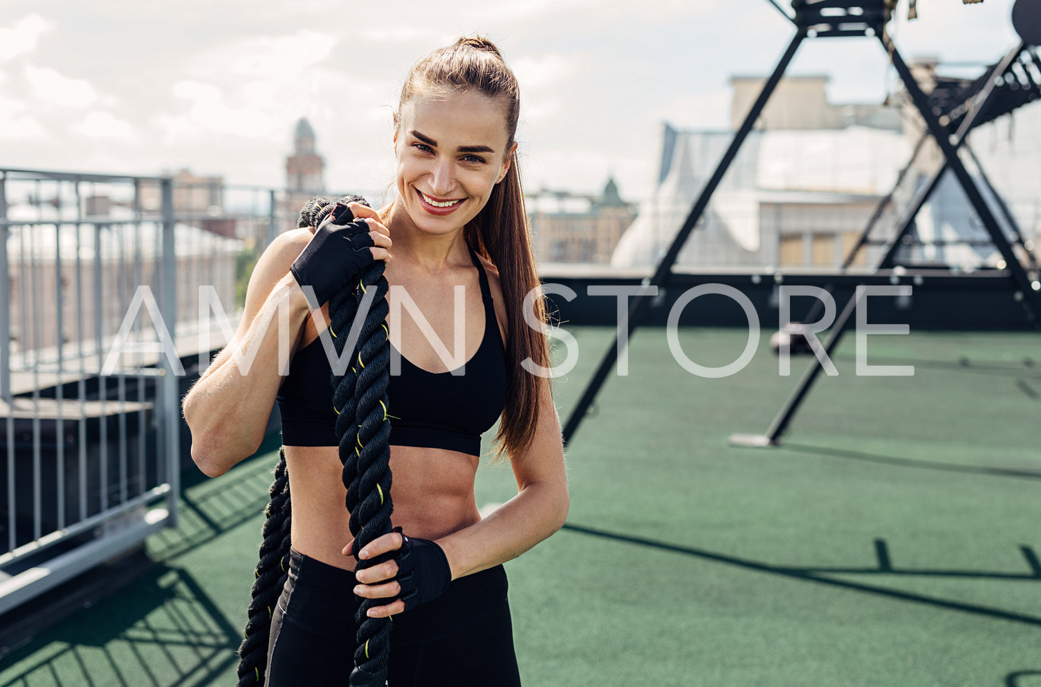 Smiling fitness woman holding battle ropes looking at camera after training	
