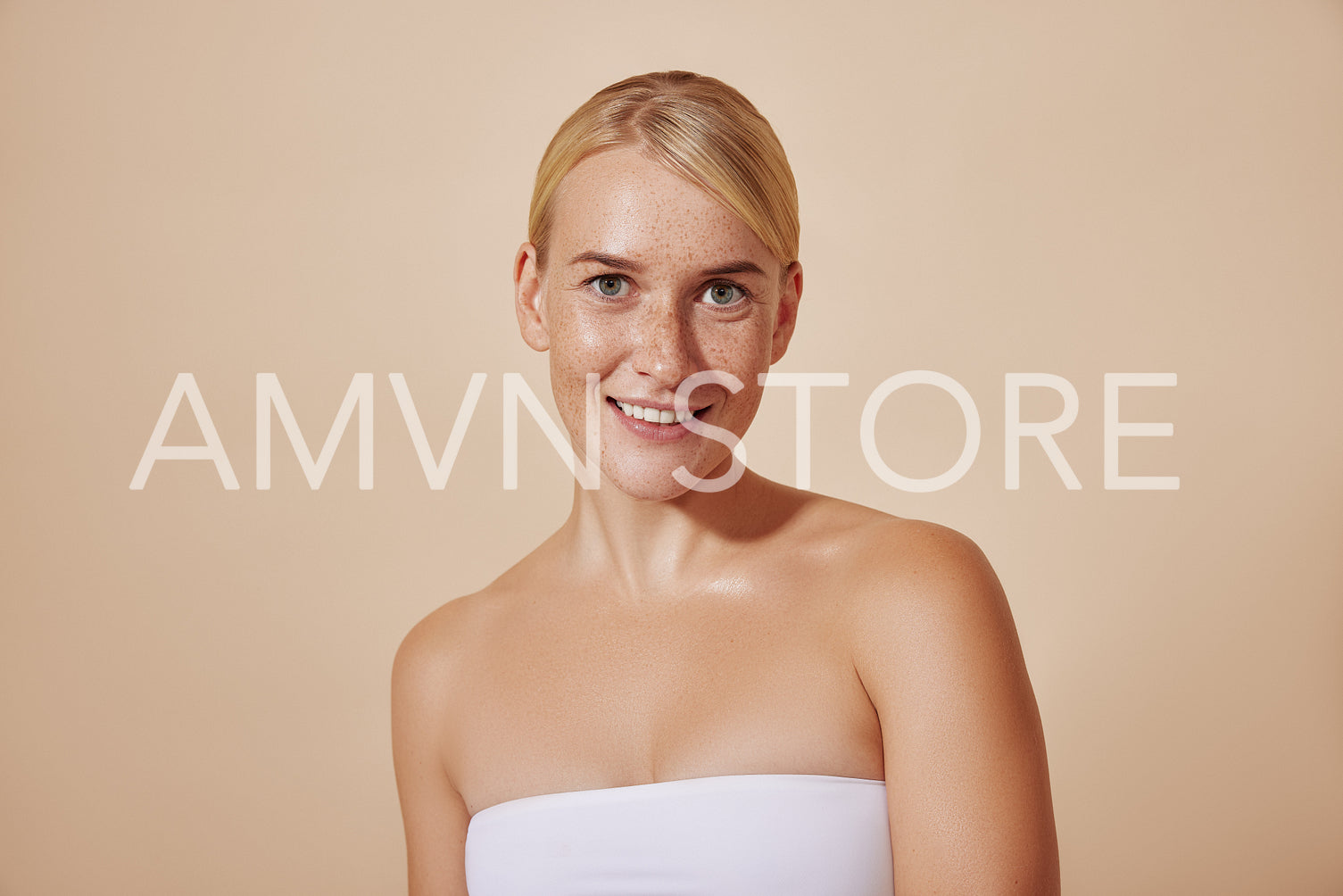 Young smiling female with freckles looking at the camera. Beautiful woman with blond hair and perfect skin.