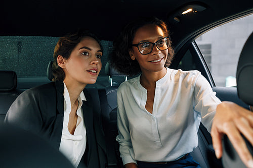 Two business colleagues sitting on a backseat of a taxi and looking away