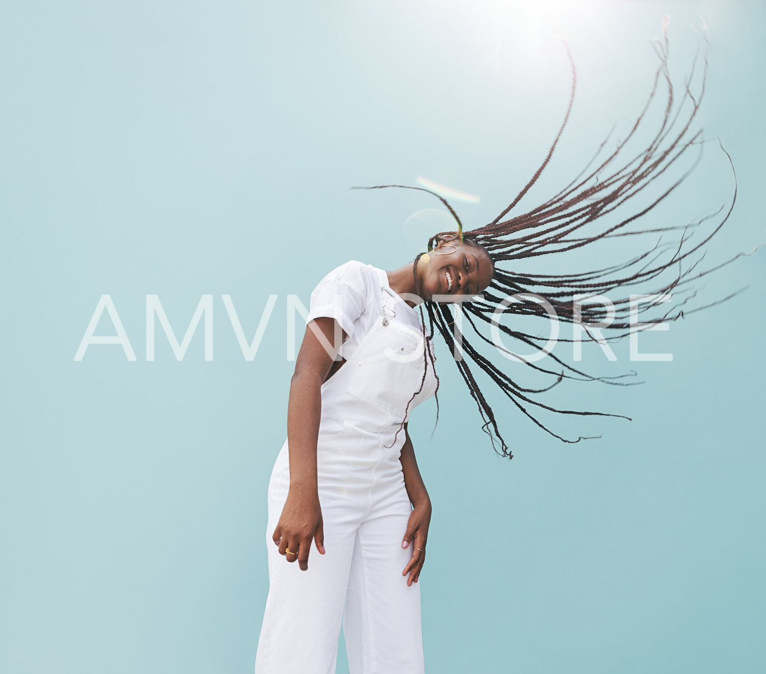 Young happy female in white casuals having fun against the blue wall. Girl with long braids enjoying a sunny day.