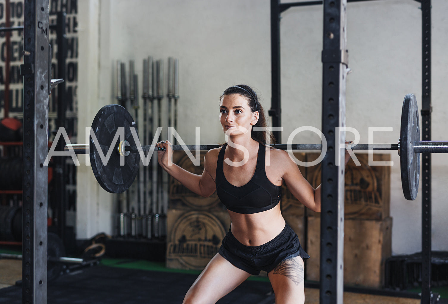 Young woman exercising with barbell in a sport club, doing squats	